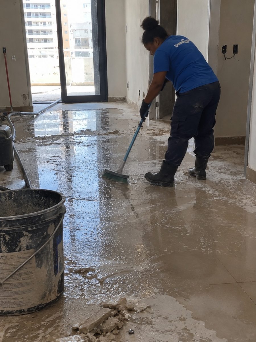 Profissional da Donna Clean esfregando o piso com resíduos de obra em apartamento